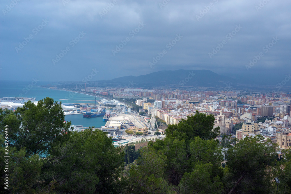 Malaga, Spain, February 2019. Panorama of the Spanish city of Malaga. Buildings, port, bay, ships and mountains against a cloudy sky. Dramatic sky over the city. Beautiful view.