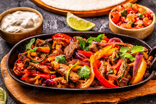 FAJITAS with colored pepper and onions, served with tortillas.