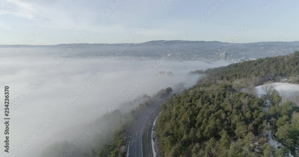 4K aerial video with forward motion and a high angle view of the beautiful hills of Ekeberg in Oslo the skyline covered in thick fog at daytime. 4K aerial video with forward motion and a high angle view of the beautiful hills of Ekeberg in Oslo the skyline covered in thick fog at daytime.