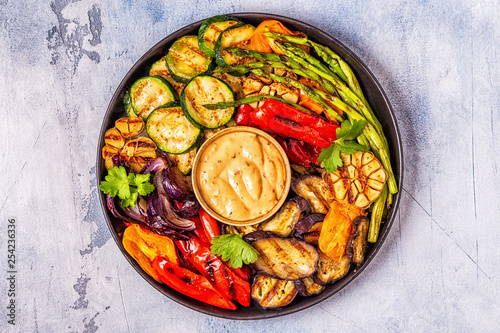 Grilled vegetables on a plate with sauce.