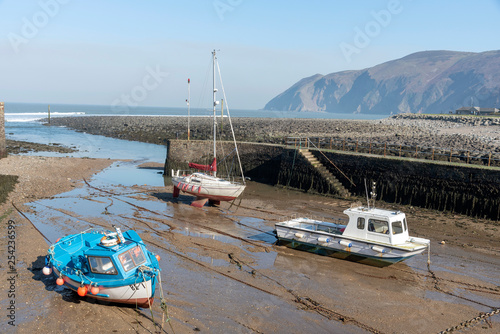 Lynmouth, North Devon, England, UK. March 2019. Lynmouth pier and  small boats on the West Lyn River at low tide where it meets the Bristol Channel. photo