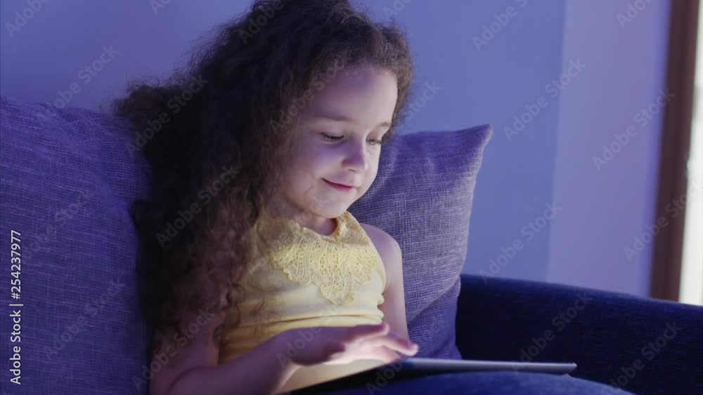 Night Shot Portrait of a Caucasian Cute Child, Little Baby Girl Close Up of a Child's Face Viewing a Tablet PC With a Reflection of and Pictures in His Eyes. Night Shot Portrait of a Caucasian Cute Child, Little Baby Girl Close Up of a Child's Face Viewing a Tablet PC With a Reflection of and Pictures in His Eyes.