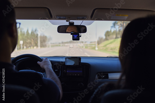 European man with the girlfriend by his side is driving the car on the roadway.