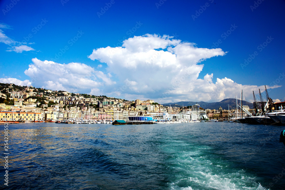  Beautiful view of the rocky mountains, the Italian city of Genoa, the port and the ships. Blue sky with white cloud. Blue ocean.