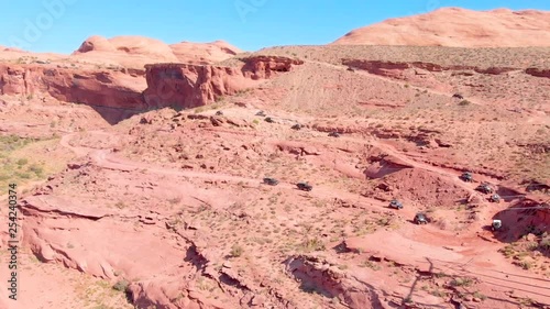 Aerial shot of a group of off-road UTV vehicles climbing a red rock mountain in Moab, Utah. photo