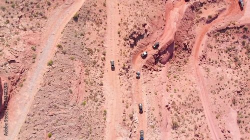 Bird's-eye view aerial shot of a group of off-road UTV vehicles climbing a red rock mountain in Moab, Utah. photo