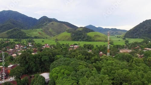 Aerial shot of a cellphone tower in a small city of a rural area with some green environment with a lot of nature and small houses photo