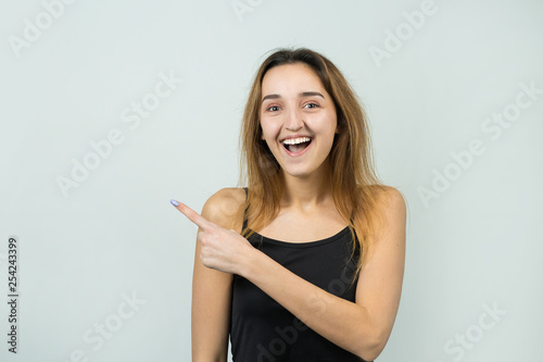 Happy young caucasian female in a T-shirt pointing fingers away, showing copy space for your text.