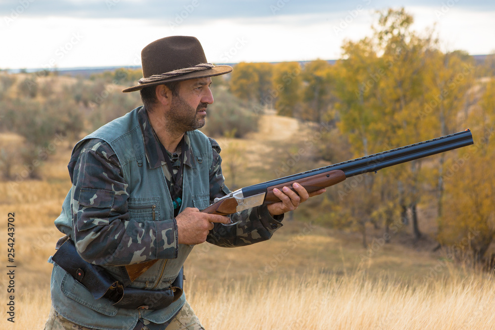 Hunter with a hat and a gun in search of prey in the steppe Hunter with a hat and a gun in search of prey in the steppe