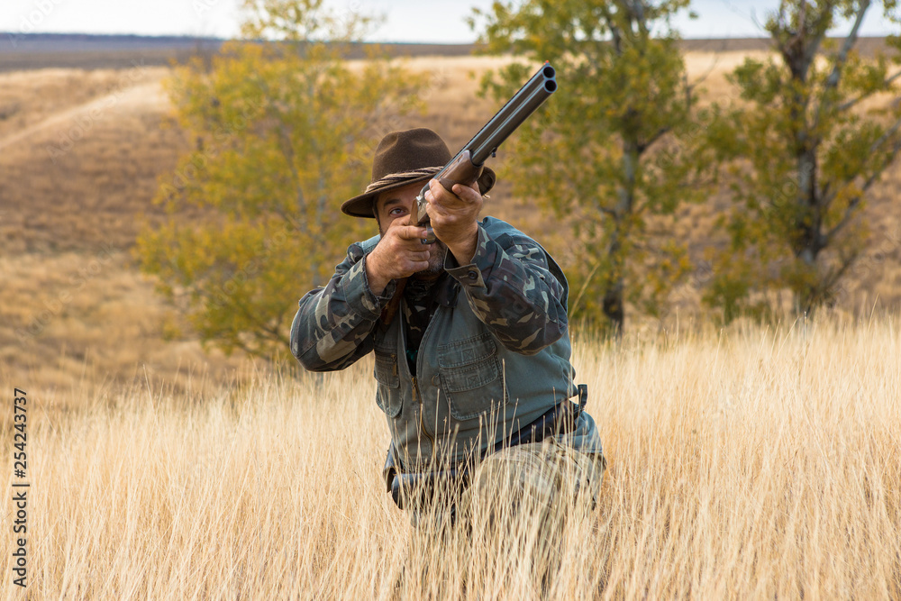 Hunter with a hat and a gun in search of prey in the steppe Hunter with a hat and a gun in search of prey in the steppe