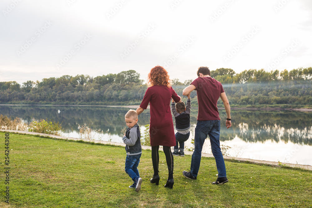 Parent, childhood and nature concept - Family playing with two sons by the water