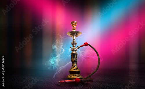 Hookah with smoke on the background of an empty scene, wet asphalt and colored neon light, blurry lights of the night city, bokeh