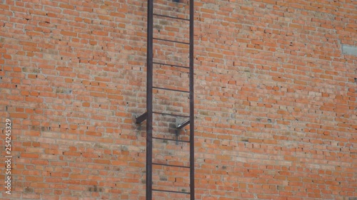 Staircase from metal on brick wall background. Movement up. Fire escape hugs facade.