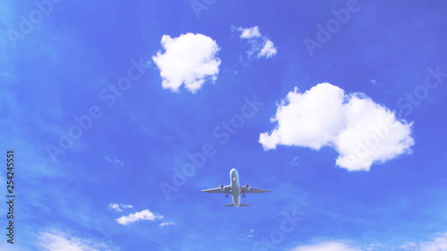 airplane in the blue sky with clouds, view from below of flying aeroplane. low angle shot background with copy space.