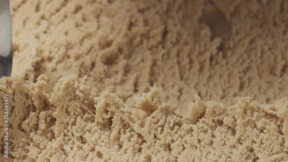 Slow motion closeup hazelnut praline ice cream scooping with spoon Slow motion closeup hazelnut praline ice cream scooping with spoon