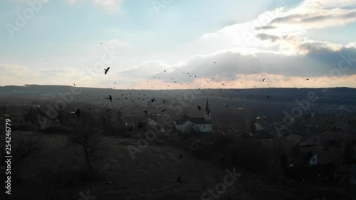 Silhouette Flock of Crows Circling Above White Church, Bad Omen. photo