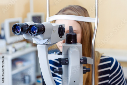 Valokuvatapetti a young woman examines the eyes of an ophthalmologist on a slit lamp, slit lamp