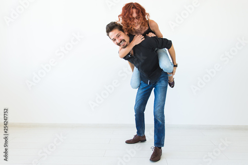 People and love concept - Beautiful pretty woman sitting at man's back and embracing him on whi