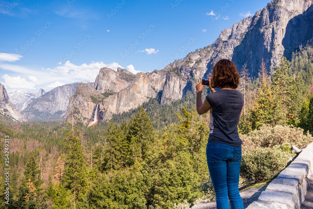 Young woman is taking a photo of Yosemite valley from Tunnel View in Yosemite National park, United states of America