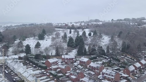 Forward tracking drone shot of snowy Exeter over a wooded area CROP photo