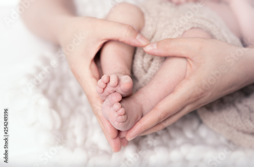 Winzige Babyfüße in den herzförmigen Händen der Mutter