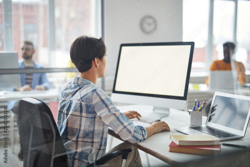 Busy young manager in casualwear sitting in front of computer monitor while working in office Busy young manager in casualwear sitting in front of computer monitor while working in office