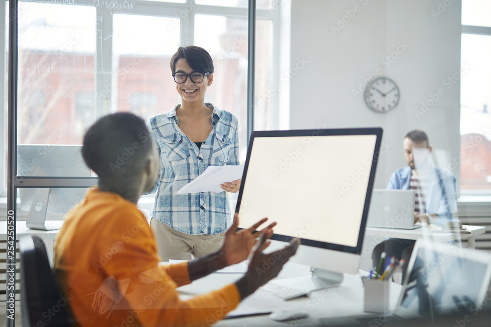 Two young casual managers preparing for conference or seminar and discussing their ideas for report