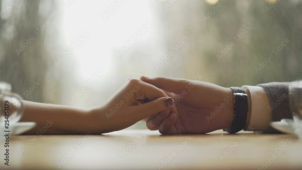 Young couple holding hands at the cafe