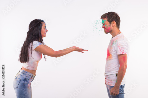 Holiday, holi and people concept - Happy couple having fun covered in paint on white background