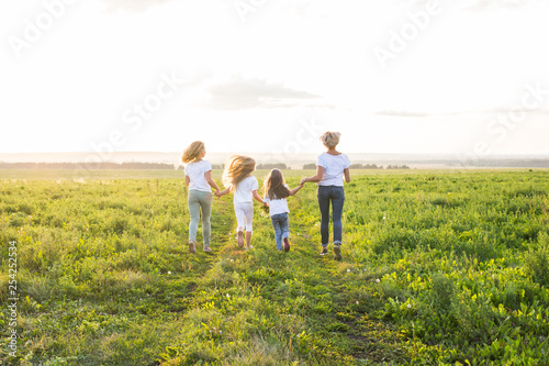 Family, fun and holiday concept - Mothers and her daughters going away in green field