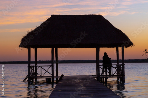 Bacalar, Mexico -January 20,2019  Friends watching the sunset at the pier of the Bacalar Lagoon(lagoon of the seven colors) Quintana Roo Mexico © @Nailotl