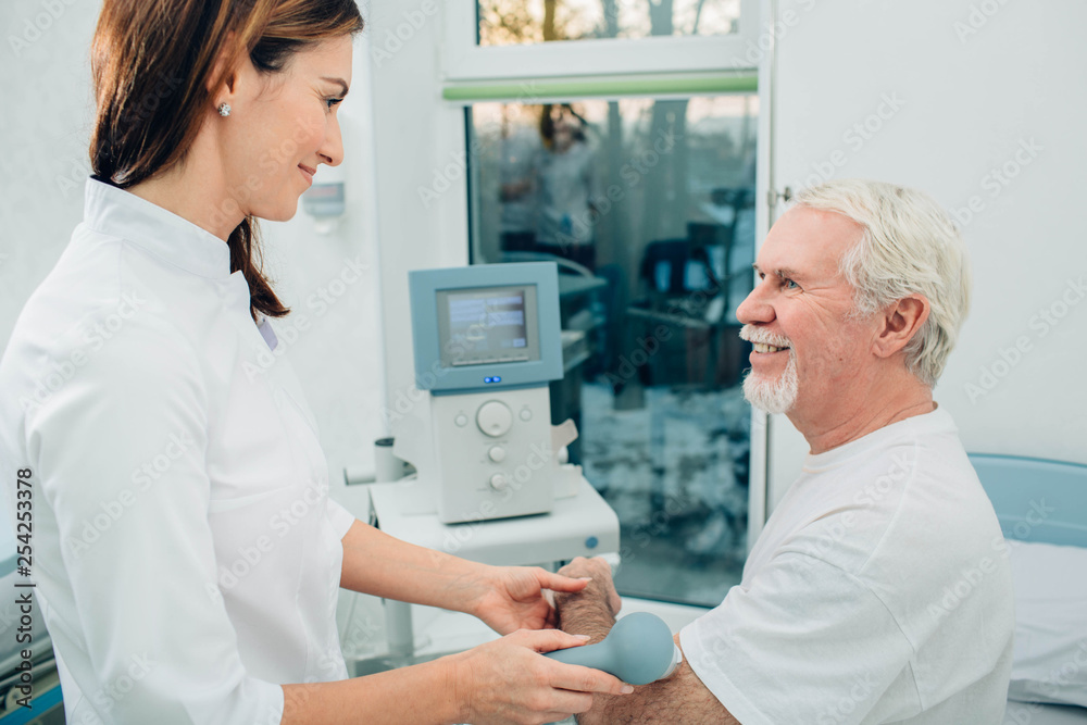 physiotherapist using ultrasound machine on hand of client in clinic. Physiotherapeutic treatment physiotherapist using ultrasound machine on hand of client in clinic. Physiotherapeutic treatment