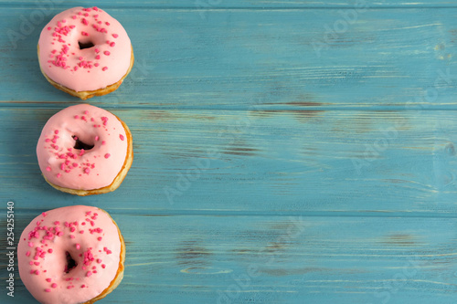 Photo with donuts and marshmallows on a blue wooden background. Sweets on a dark background. Pink donuts