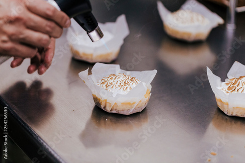Tartlet with a meringue and kitchen torch blowtorch with blue flame. woman hand holdings blowtorch. bakery concept photo