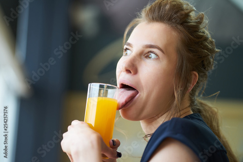 Redhead girl making faces during drinking orange juice