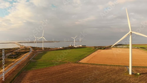 Windturbines during sunset in the south west of the Netherlands. Dynamic aerial shots with sun light. Moving slowly forward, high above ground. photo