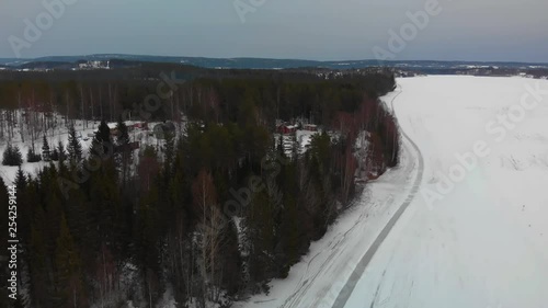 Aerial footage of a red cabin in the snow located close to Indalsalven, Timra, Sundsvall, Sweden photo