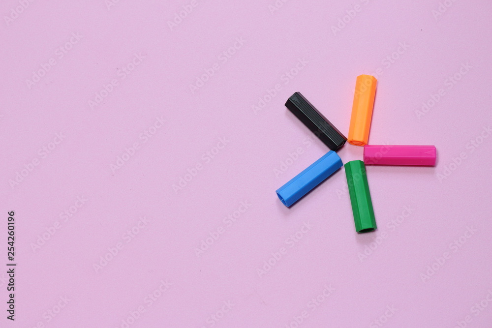 Five colorful pen cap on a pink millennial background. Space to insert the text. Office stuff. Minimalism. Metaphor to teamwork and hierarchy Five colorful pen cap on a pink millennial background. Space to insert the text. Office stuff. Minimalism. Metaphor to teamwork and hierarchy