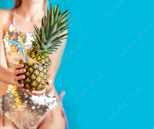 tropical pineapple juice in the hands of a girl in a brilliant swimsuit