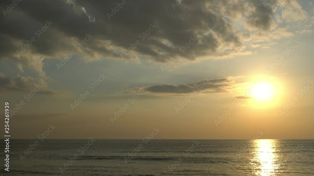 Tranquil scene of sun setting on placid ocean on warm day Tranquil scene of sun setting on placid ocean on warm day