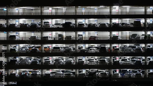 A night timelapse shot of a multilevel garage with lots of cars parking and leaving the place.