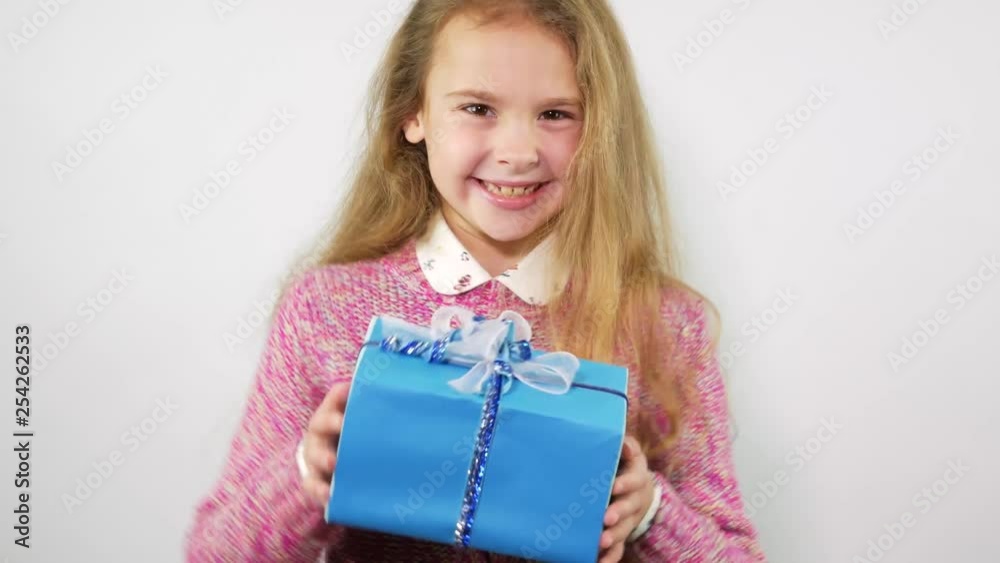 Teenage girl rejoices the present. Blue box with a gift Teenage girl rejoices the present. Blue box with a gift