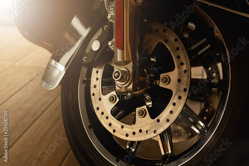 front fork of a motorcycle with a front wheel, brake disc, brake cylinder. Close up. Soft focus