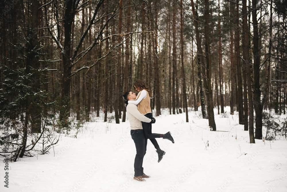 Winter love story on ice. Stylish guy and girl with walk in snowy forest. Romance