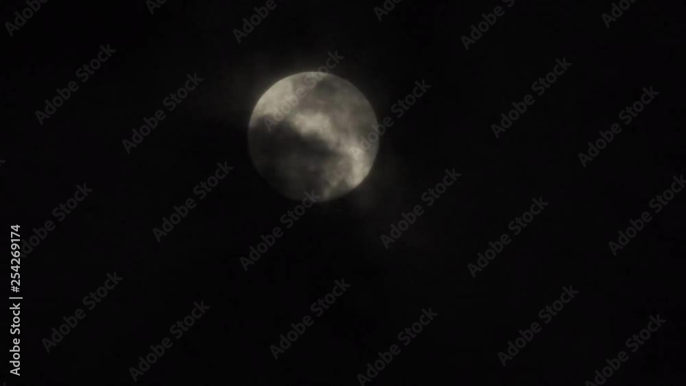 Moon covered by dark and translucent clouds close up Moon covered by dark and translucent clouds close up