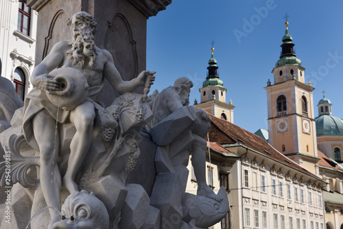 Detail of the Robba marble scultpure on The Fountain of the Three Rivers at Town Square Ljubljana Slovenia with St Nicholas church Cathedral photo