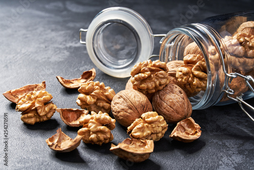 Walnut in an open glass jar on black table, close-up.