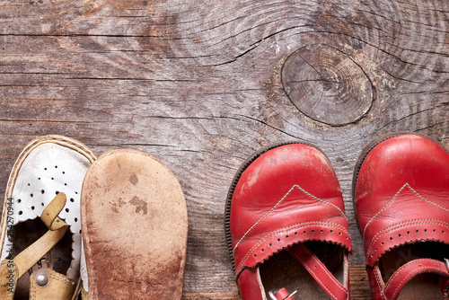 Children oldfashioned footwear on vintage wood background top view. Childhood memory