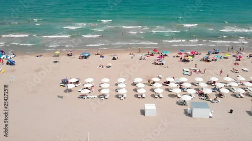 Aerial footage of the beach umbrellas and surf board rental at Alicante Beach, moving sideways photo