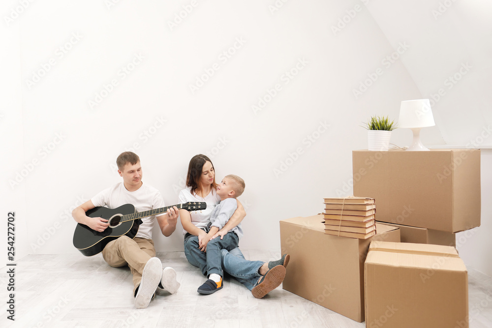 Young family, man woman and child son in new apartments. Boxes with cargo on a white background. Young family, man woman and child son in new apartments. Boxes with cargo on a white background.